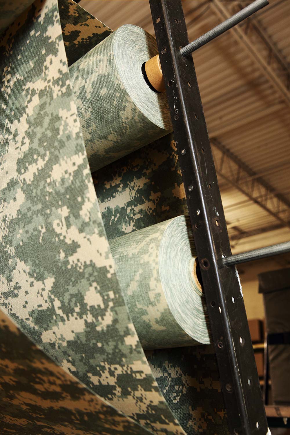 military-camo-fabric-rolls-berry-amendment-ehmke Bulk rolls of Berry Amendment compliant military camouflage fabric stored in production racks.