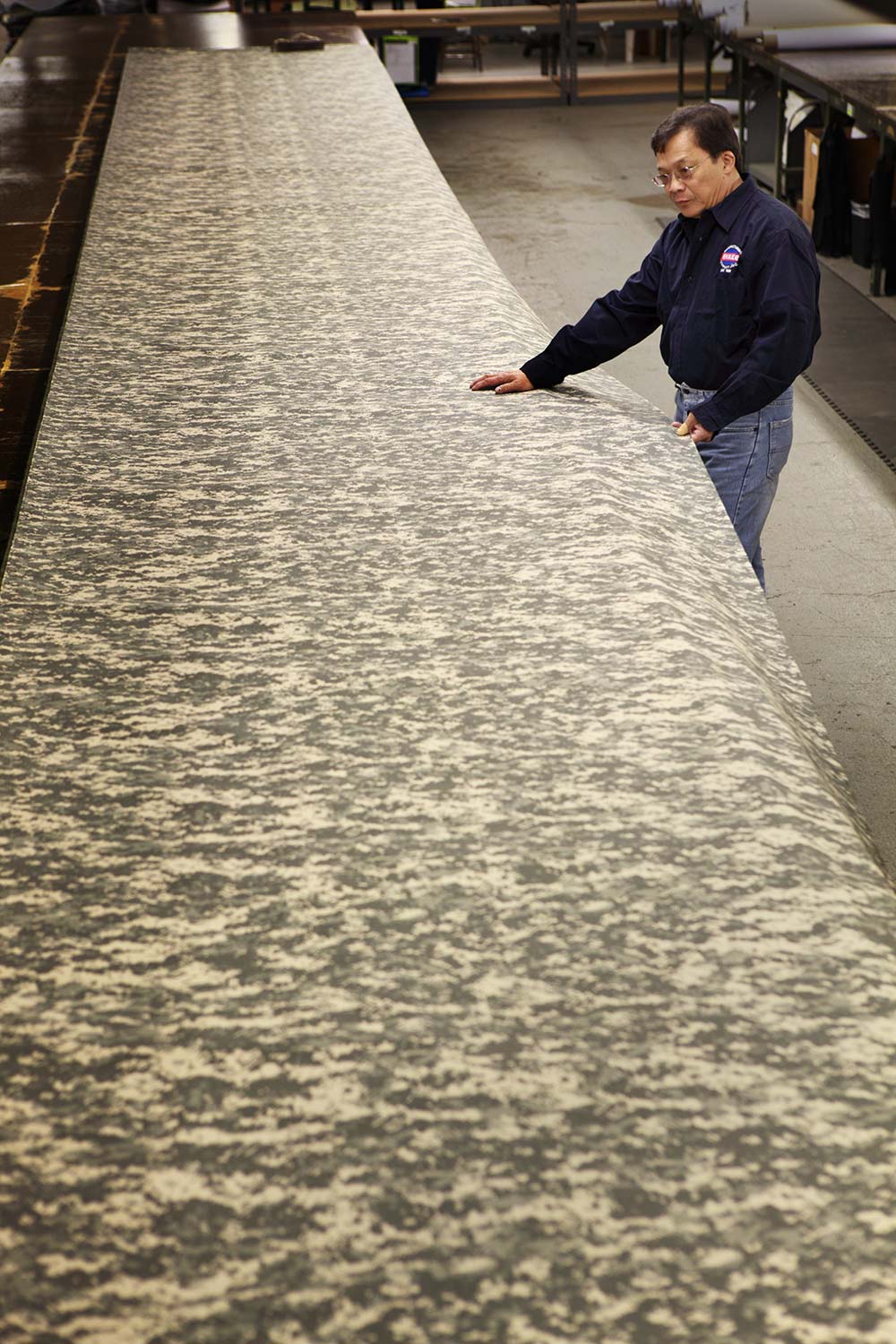 Technical fabric specialist inspecting rolls of military camouflage material at Ehmke Manufacturing.
