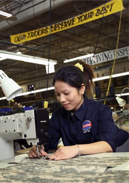 Technician operating an industrial sewing machine to assemble military textile gear.